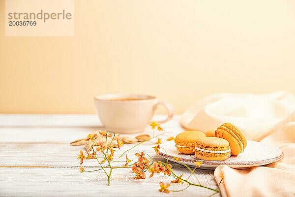 Orangenmakronen oder Makronen Kuchen mit einer Tasse Aprikosensaft auf einem weißen hölzernen Hintergrund und orangefarbenen Leinenstoff. Seitenansicht  Kopierraum  selektiver Fokus