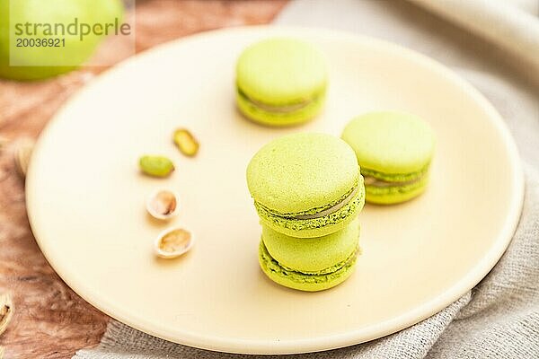 Grüne Macarons oder Makronen Kuchen mit Tasse Kaffee auf einem braunen Beton Hintergrund und Leinen Textil. Seitenansicht  Nahaufnahme  selektiver Fokus