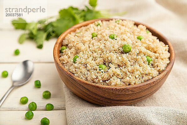 Quinoa Brei mit grüner Erbse in einer Holzschale auf weißem Holzhintergrund und Leinenstoff. Seitenansicht  Nahaufnahme  selektiver Fokus