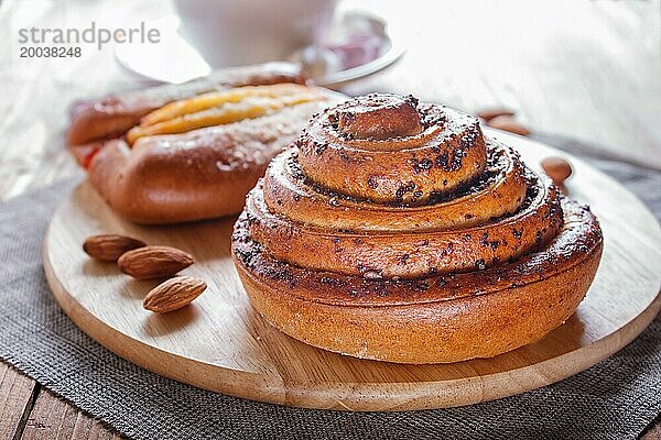 Eine Tasse heiße Schokolade und Brötchen auf braunem Holzhintergrund. Nahaufnahme