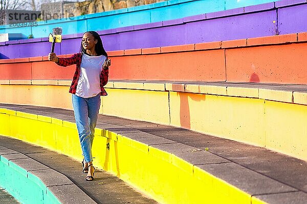 Eine junge Afrikanerin  die Inhalte für soziale Medien erstellt  nimmt sich selbst in einem bunten Stadtpark auf
