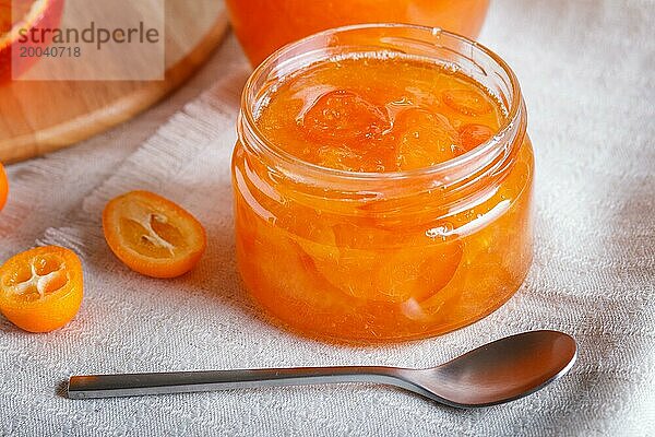 Orangen und Kumquatmarmelade in einem Glas mit frischen Früchten auf einer weißen Leinentischdecke. Hausgemacht  Nahaufnahme