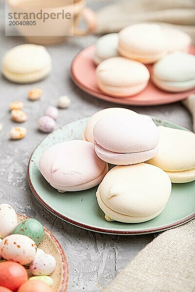 Farbiger Zephir oder Marshmallow mit Kaffeetasse und Dragees auf grauem Betonhintergrund und Leinenstoff. Seitenansicht  Nahaufnahme  selektiver Fokus