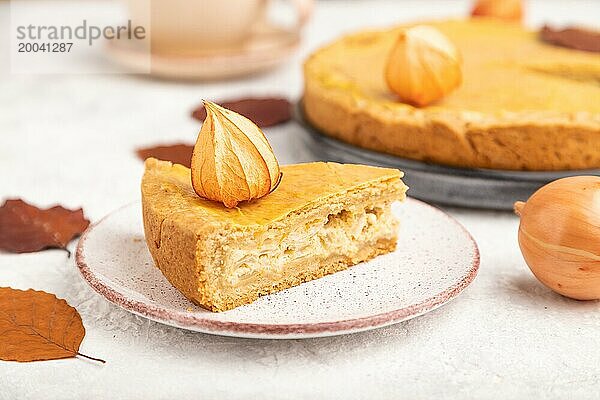 Herbst Zwiebelkuchen mit Blättern und Tasse Kaffee auf grauem Beton Hintergrund dekoriert. Seitenansicht  Nahaufnahme  selektiver Fokus