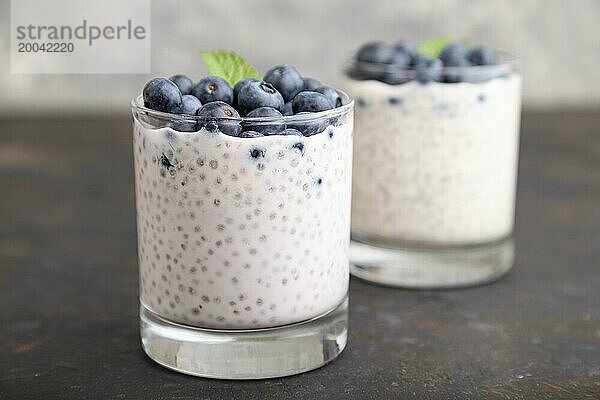 Joghurt mit Heidelbeeren und Chia im Glas auf schwarzem Betonhintergrund. Seitenansicht  Nahaufnahme