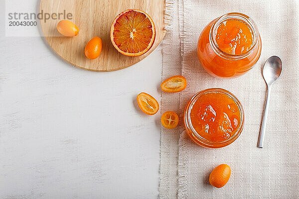 Orangen und Kumquatmarmelade in einem Glas mit frischen Früchten auf weißem Hintergrund. Hausgemacht  Kopierraum  Draufsicht