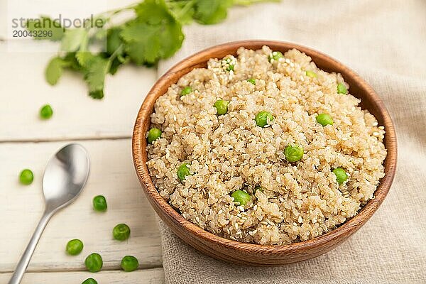 Quinoa Brei mit grüner Erbse in einer Holzschale auf weißem Holzhintergrund und Leinenstoff. Seitenansicht  Nahaufnahme  selektiver Fokus