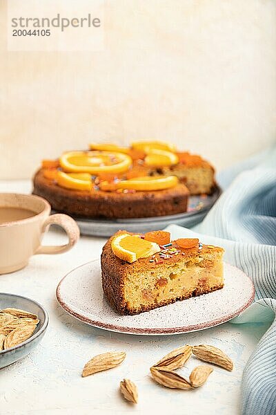 Orangenkuchen mit Mandeln und einer Tasse Kaffee auf einem weißen Betonhintergrund und blauem Leinentuch. Draufsicht  Nahaufnahme  selektiver Fokus