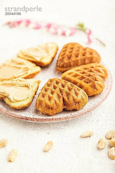 Hausgemachte Waffel mit Erdnussbutter und Tasse Kaffee auf einem grauen Betonhintergrund. Seitenansicht  Nahaufnahme  selektiver Fokus