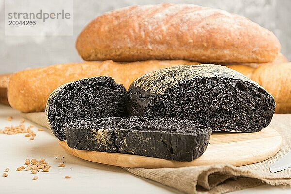 Aufgeschnittenes Schwarzbrot mit verschiedenen Arten von frisch gebackenem Brot auf weißem Holzhintergrund. Seitenansicht  Nahaufnahme  selektiver Fokus