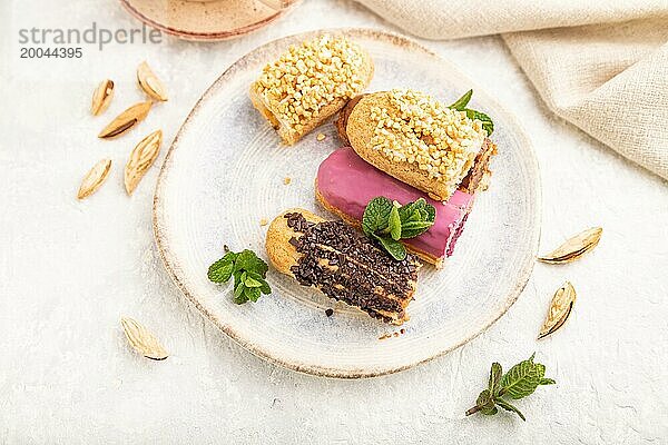 Set von Eclair  traditionelles französisches Dessert und Tasse Kaffee auf grauem Betonhintergrund und Leinenstoff. Seitenansicht  Nahaufnahme  selektiver Fokus  Stillleben. Frühstück  Morgen  Konzept