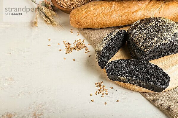 Aufgeschnittenes Schwarzbrot mit verschiedenen Arten von frisch gebackenem Brot auf weißem Holzhintergrund. Seitenansicht  Nahaufnahme  Kopierraum