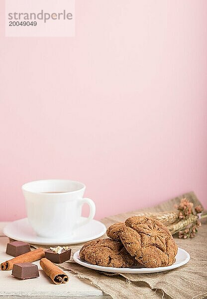 Hausgemachte Haferflockenkekse mit einer Tasse Kakao auf einem Leinenstoff und rosa Pastellhintergrund. Seitenansicht  Nahaufnahme  selektiver Fokus  Kopierraum