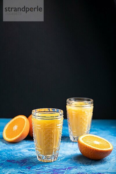 Glas Orangensaft auf einem schwarzen und blaün Hintergrund. Hartes Licht  Kontrast. Seitenansicht  Kopierraum