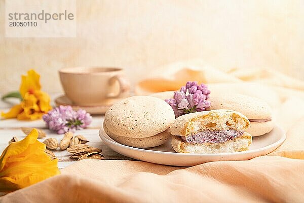 Meringues Kuchen mit einer Tasse Kaffee auf einem weißen Holzhintergrund und orangefarbenem Leinenstoff. Seitenansicht  Nahaufnahme  selektiver Fokus