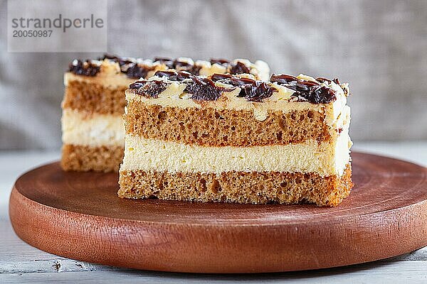 Ein Stück Kuchen mit Milch und Buttercreme auf einem hölzernen Küchenbrett  Nahaufnahme  selektiver Fokus  weißer Hintergrund