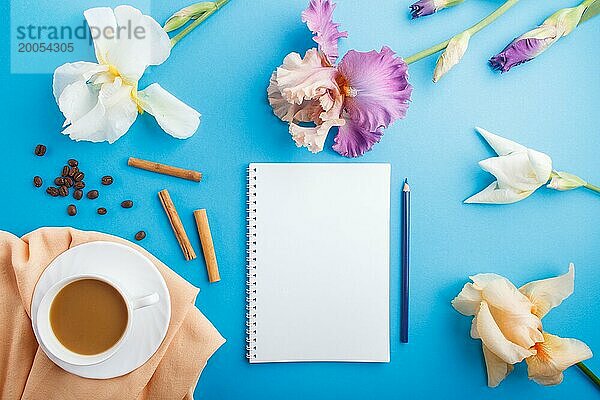 Orange  weiß  lila Iris Blumen mit Notebook und eine Tasse Kaffee auf pastellblauem Hintergrund. Morninig  Frühling  Mode Zusammensetzung. Flachlage  Draufsicht  Kopierraum
