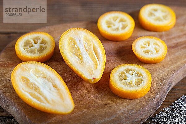 In Scheiben geschnittene Kumquats auf einem hölzernen Küchenbrett  Nahaufnahme  selektiver Fokus