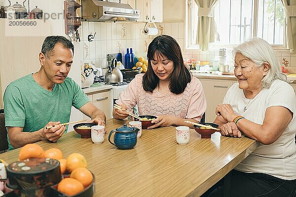 Japanische erwachsene Familie isst Reis mit Stäbchen. Die weißhaarige ältere Mutter genießt es  ihre erwachsenen Kinder beim typischen japanischen Mittagessen zu beobachten