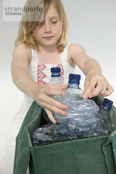 Junges Mädchen  das Plastikwasserflaschen recycelt