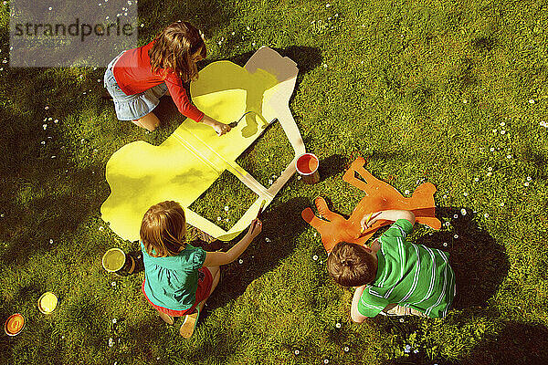 Kinder malen Pappausschnitte im Garten