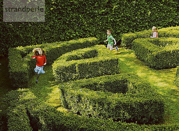 Kinder laufen im Gartenlabyrinth