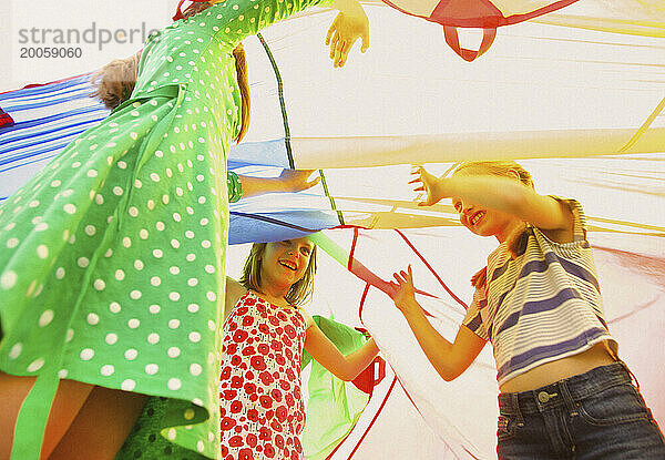 Kinder spielen unter dem Fallschirm