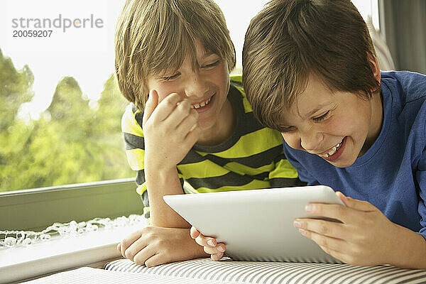 Jungen  die lächelnd ein digitales Tablet verwenden