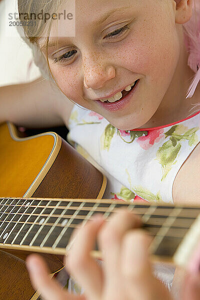 Nettes junges Mädchen  das Gitarre spielt
