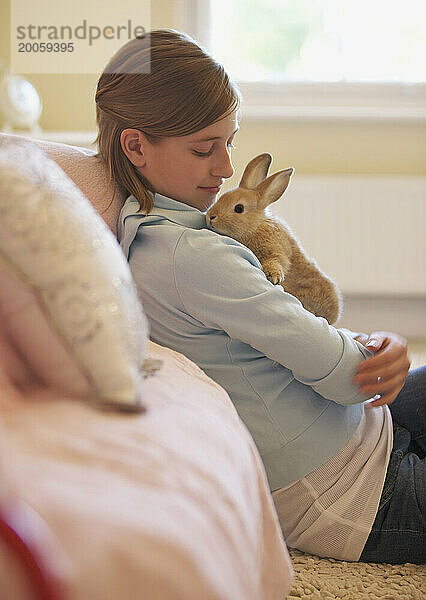 Mädchen sitzt und hält Kaninchen