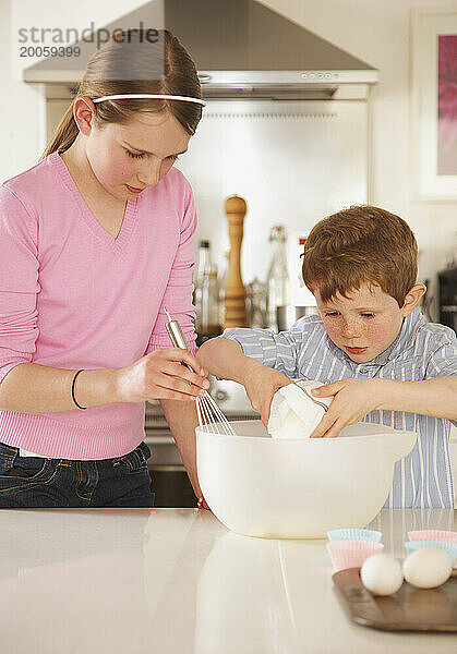 Mädchen und kleiner Junge bereiten Cupcakes zu