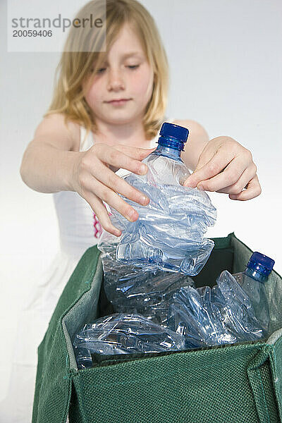 Junges Mädchen  das Plastikwasserflaschen recycelt