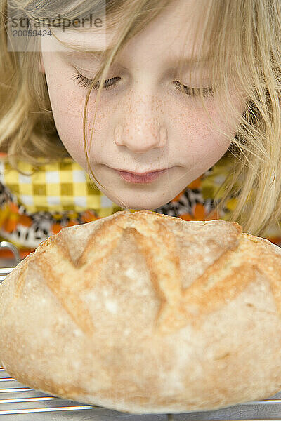 Junges Mädchen riecht an einem Laib Brot