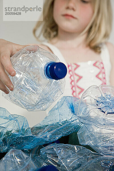 Junges Mädchen  das Plastikwasserflaschen recycelt