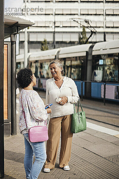 Lächelnde behinderte Frau  die mit einer Freundin spricht  während sie am Bahnhof steht