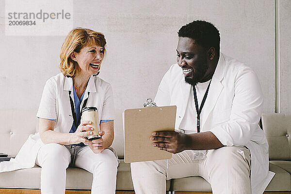 Fröhliche männliche und weibliche Ärzte sitzen auf dem Sofa im Krankenhaus