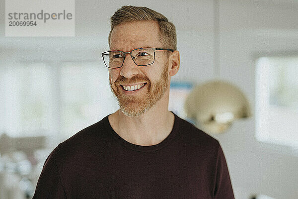 Lächelnder reifer Mann mit Brille  der auf das moderne Zuhause blickt