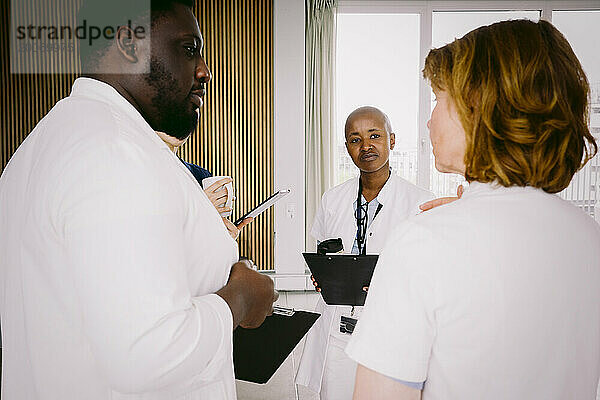 Ein Team aus multiethnischen Ärzten diskutiert  während es im Krankenhaus steht
