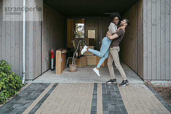 Glückliches gemischtrassiges Paar  das Spaß hat  während es am Gebäudeeingang steht