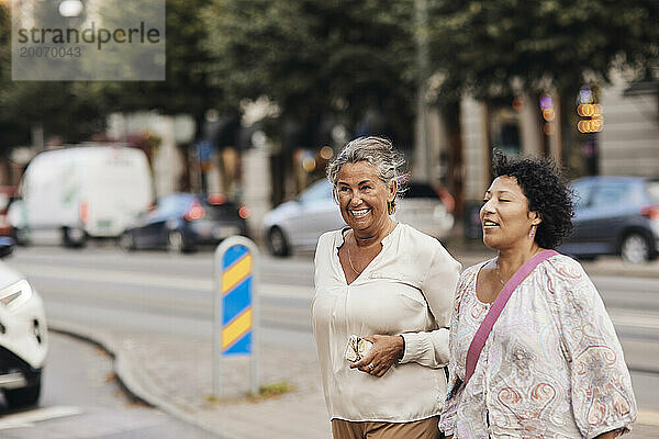 Glückliche Frau spaziert mit Freundin durch die Stadt