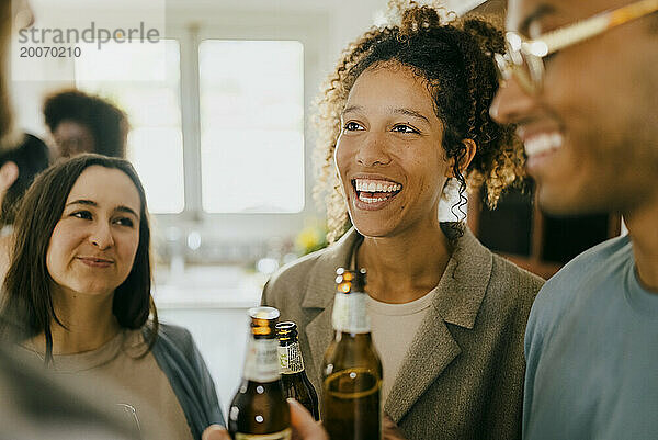 Fröhliche junge Männer und Frauen stehen mit Bierflaschen auf einer Party