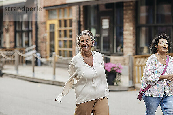 Lächelnde behinderte Frau spaziert mit einer Freundin auf der Straße