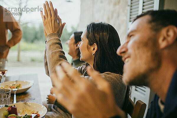 Fröhliche Freunde klatschen während der Dinnerparty auf der Terrasse