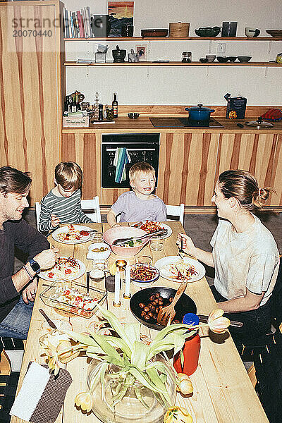 Blick aus der Vogelperspektive auf eine glückliche Familie  die Spaß beim Abendessen am Esstisch in der Küche hat