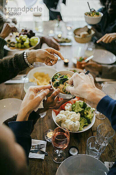 Männliche Freunde servieren Essen am Esstisch während der Dinnerparty auf der Terrasse