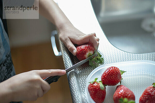 Kleiner Junge schneidet mit Hilfe seiner Mutter gesunde Erdbeeren