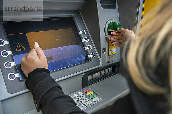 young woman taking money out of her atm  cashmachine