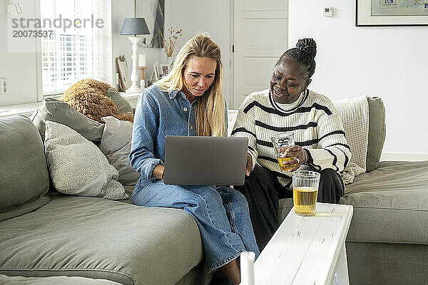 Freunde sitzen zusammen mit ihrem Laptop auf dem Sofa und planen einen Urlaub