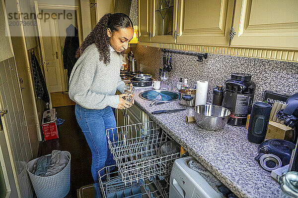Schöne Frau putzt die Küche und füttert die Spülmaschine