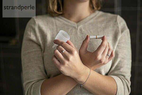 Frau hält ihre monatlichen Menstruationsgesundheitsprodukte  Tasse und Tampon in der Hand